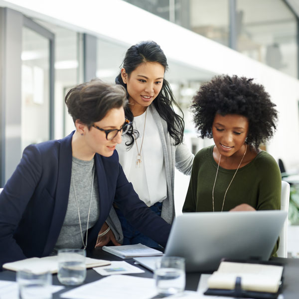 three women huddled around laptop